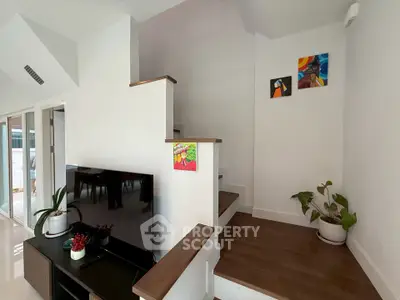 Modern interior with stylish staircase and TV area, featuring contemporary decor and natural light.