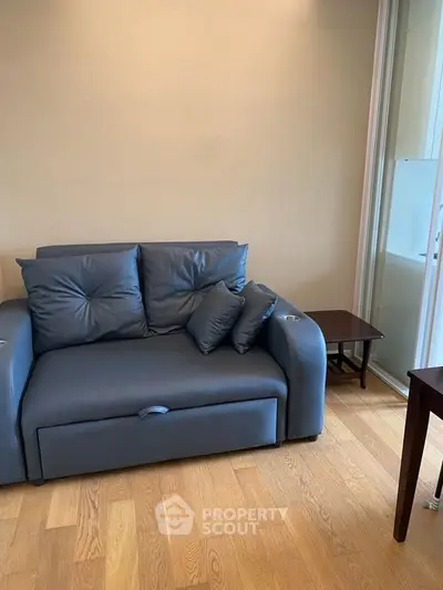 Cozy living room with modern blue sofa and wooden flooring