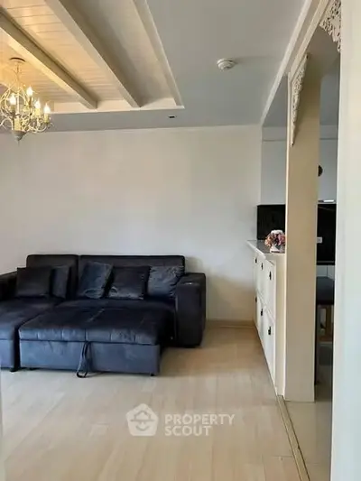 Stylish living room with elegant chandelier and modern black sofa in a cozy apartment.