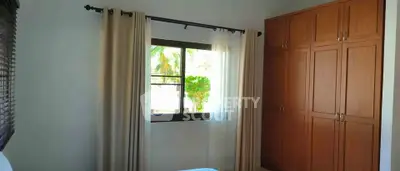 Cozy bedroom with wooden wardrobe and window view, perfect for serene living.