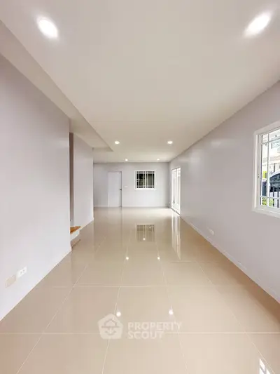 Spacious empty room with glossy tiled floors and large windows