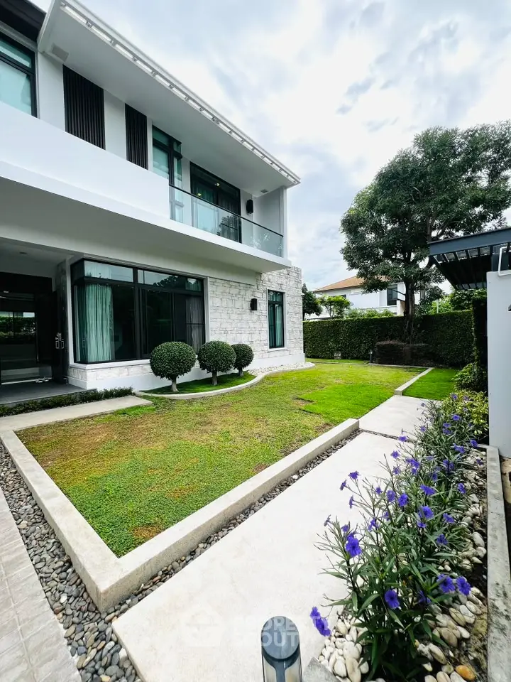 Modern two-story house with landscaped garden and large windows, perfect for family living.