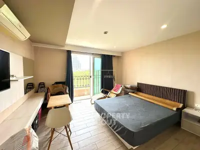 Spacious studio apartment with modern furnishings and balcony view, perfect for urban living.