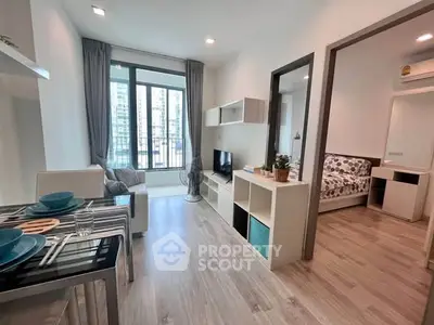 Modern open-plan living room with dining area and bedroom view in a stylish apartment.
