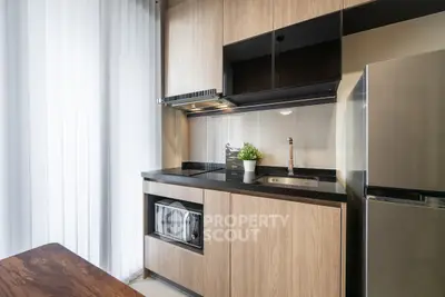 Modern kitchen with sleek cabinetry, built-in microwave, and stainless steel fridge in a stylish apartment.