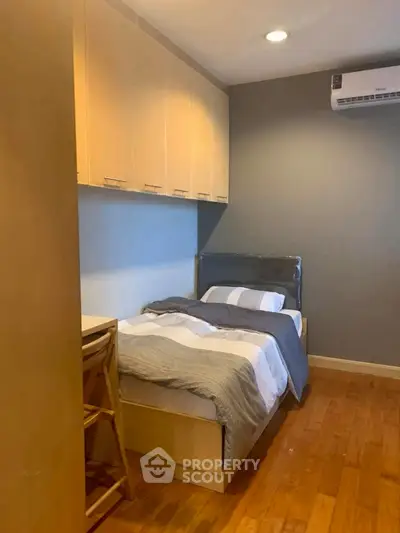 Cozy bedroom with wooden flooring and modern air conditioning