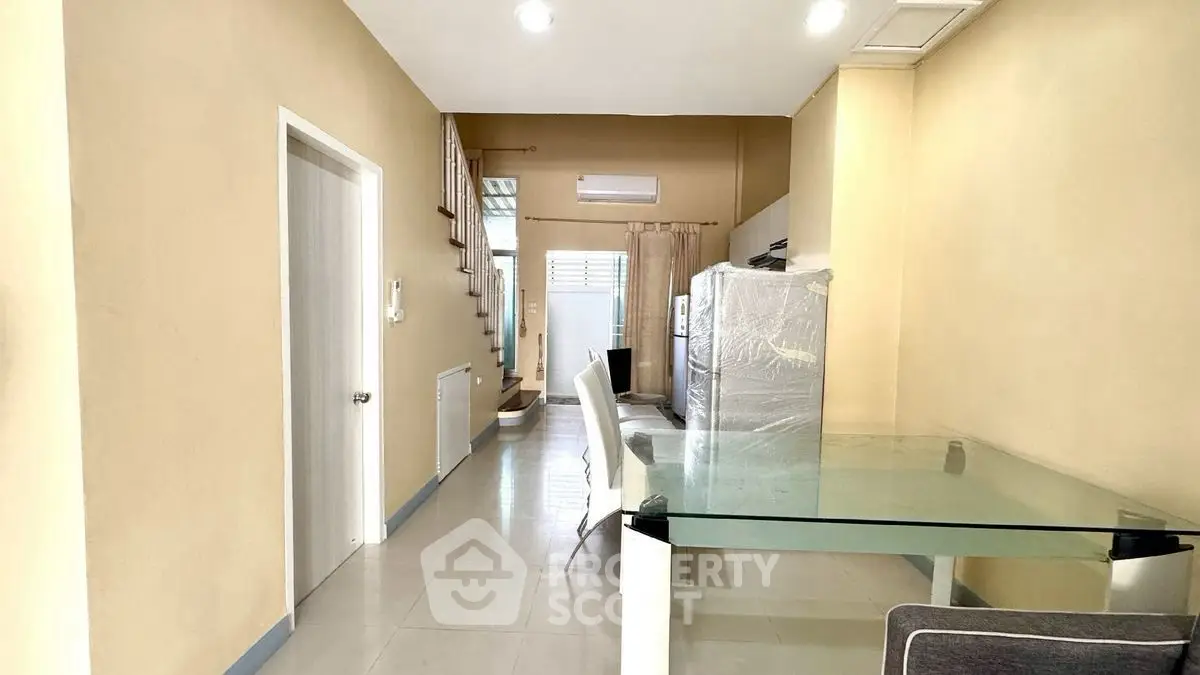 Spacious dining area with glass table and modern decor in a well-lit home interior.