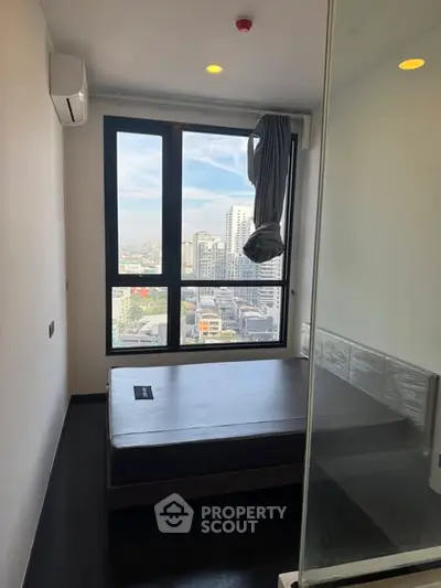 Modern bedroom with city view, featuring large window and minimalist design.