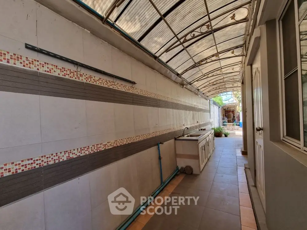 Spacious outdoor corridor with tiled walls and covered roof in modern home