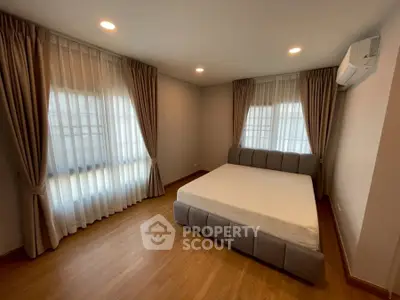 Spacious bedroom with large windows and elegant curtains in modern home.