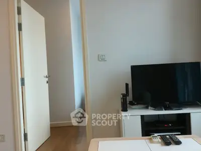 Modern living room with TV and open door, showcasing sleek design and minimalist decor.