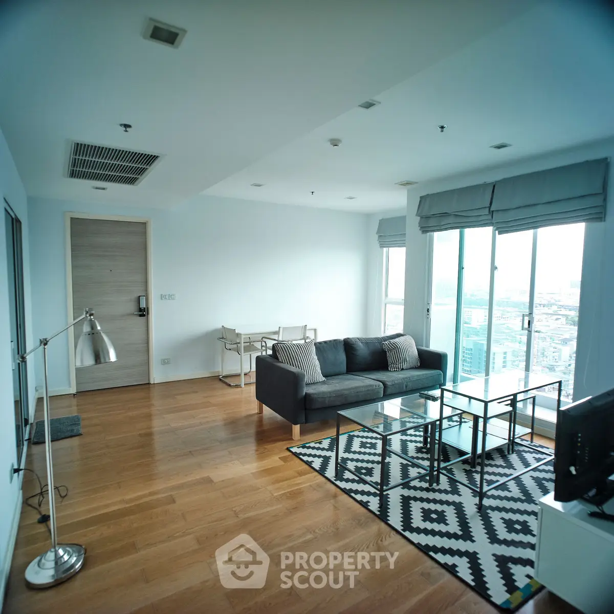 Spacious modern living room with city view, hardwood floors, and stylish decor.
