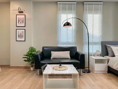 Modern living room with sleek black sofa, stylish floor lamp, and cozy decor accents.