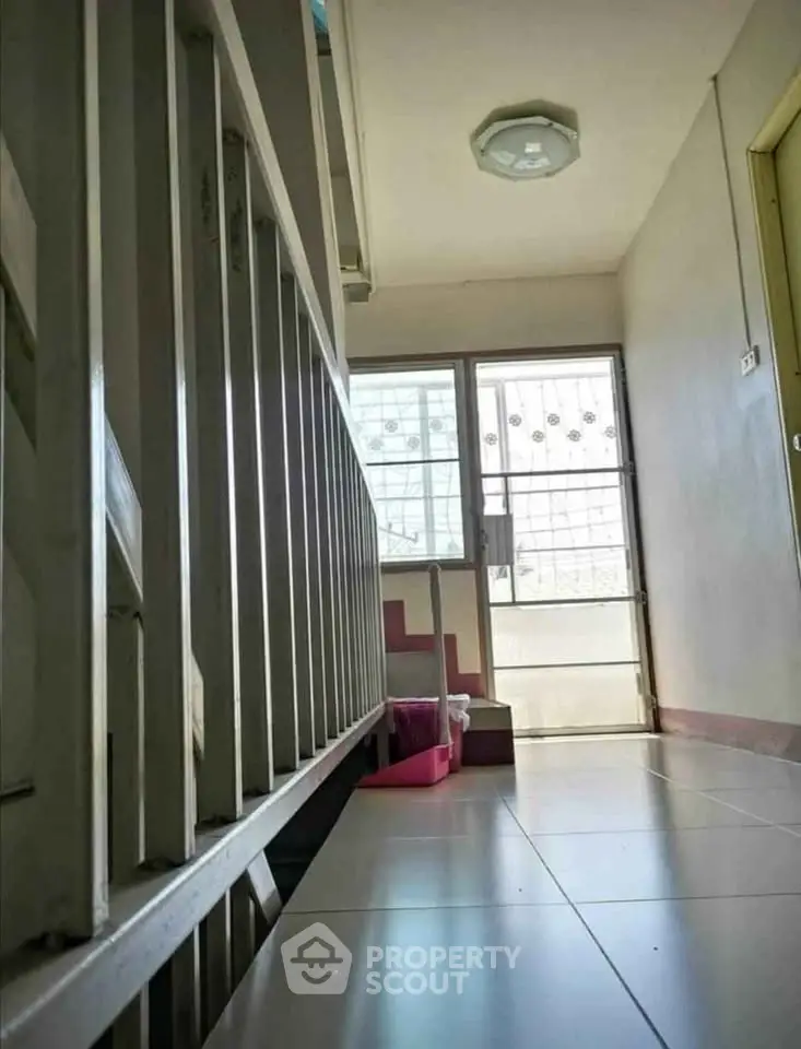 Bright corridor with tiled flooring and secure metal gate, ideal for safe and airy living spaces.