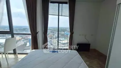 Modern bedroom with panoramic city view and large windows in high-rise apartment.