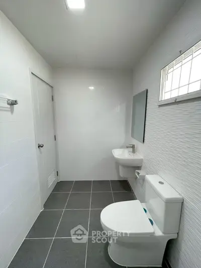 Modern bathroom with sleek fixtures and minimalist design, featuring a wall-mounted sink and toilet.