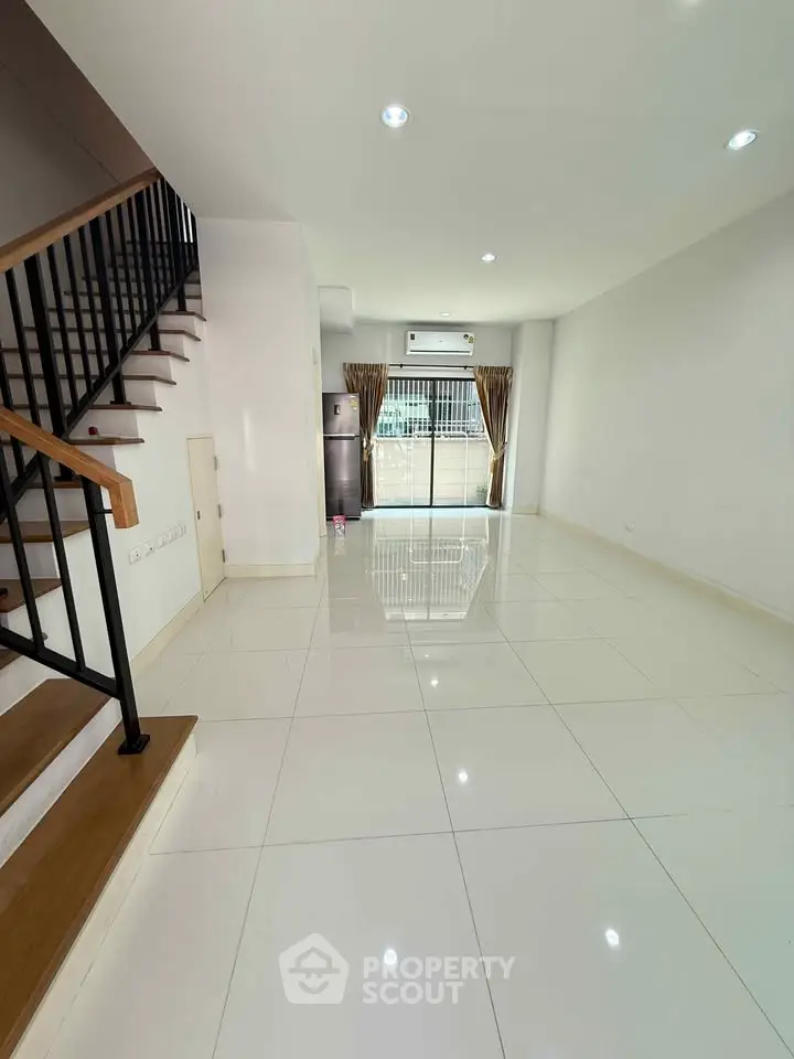 Spacious modern living room with glossy tile flooring and staircase, perfect for stylish urban living.