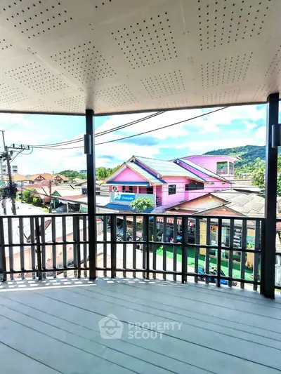 Spacious balcony with scenic view of colorful neighborhood and hills.