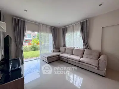 Spacious living room with large windows and garden view, featuring a comfortable sectional sofa and modern decor.