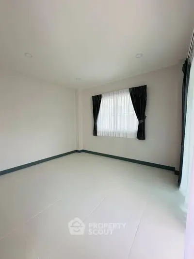 Spacious empty room with large window and elegant curtains, perfect for customization.