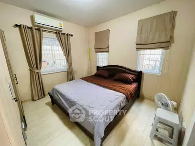 Cozy bedroom with double bed, air conditioning, and natural light from windows.