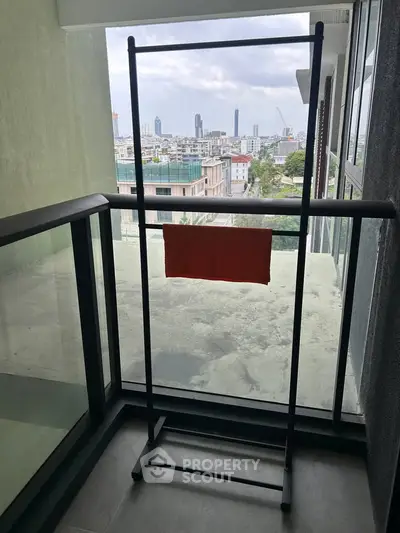 Modern balcony with city view, featuring glass railing and sleek drying rack.