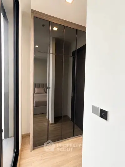 Modern bedroom with mirrored wardrobe and wooden flooring