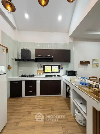 Modern kitchen with sleek cabinets, wooden flooring, and ample natural light, perfect for culinary enthusiasts.