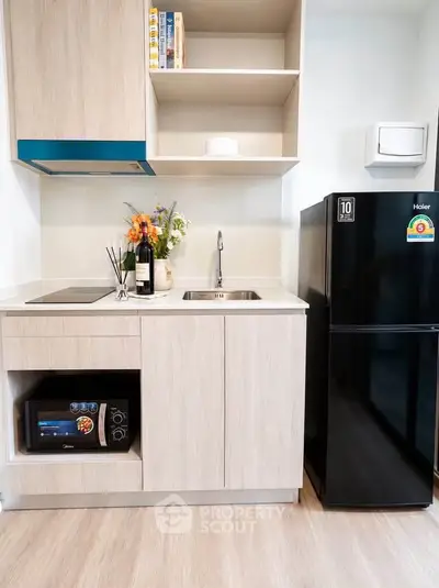 Modern compact kitchen with sleek black fridge and built-in microwave, perfect for urban living.