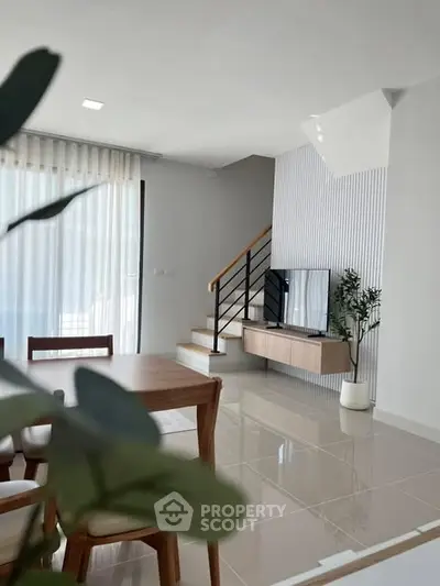 Modern living room with sleek staircase and natural light, perfect for stylish urban living.