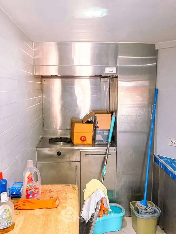 Compact kitchen with stainless steel appliances and cleaning supplies, ideal for efficient urban living.