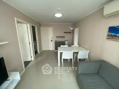 Modern living room with sleek furniture and neutral tones, featuring a compact dining area and air conditioning.