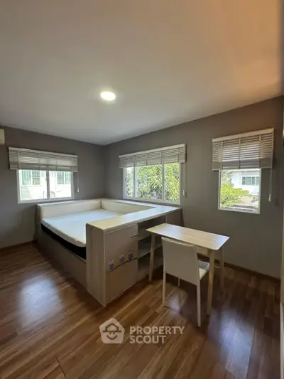 Modern bedroom with built-in bed and desk, large windows, and wooden flooring