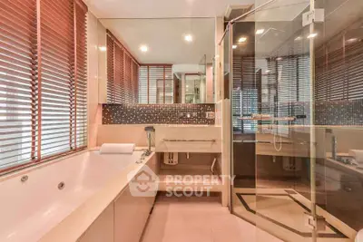 Luxurious bathroom with glass shower and large bathtub, featuring elegant tile accents and modern fixtures.