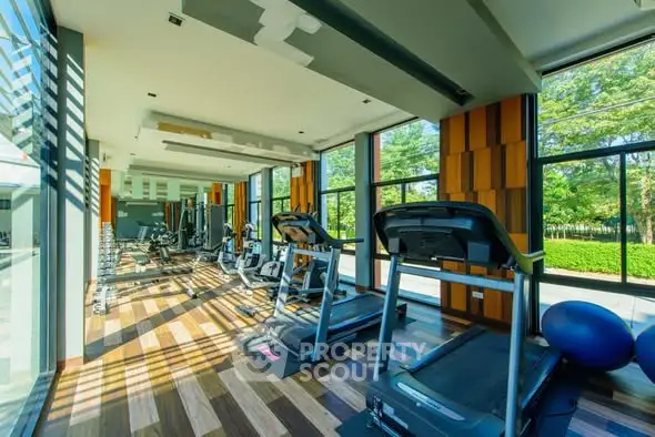 Modern gym with large windows and state-of-the-art equipment in a luxury residential building.