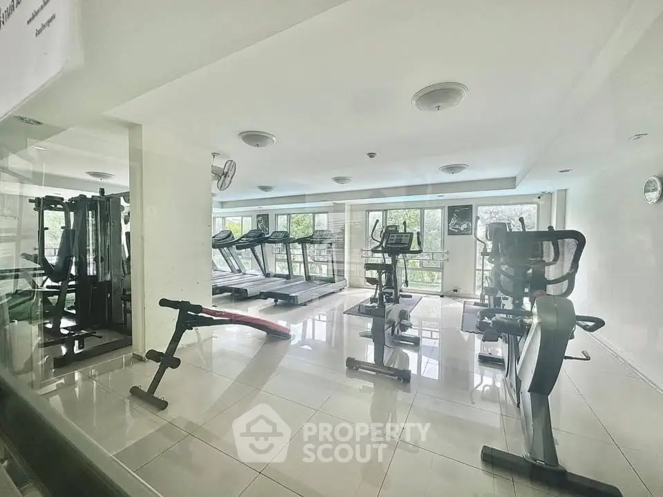 Spacious gym with modern equipment and large windows offering a refreshing view.