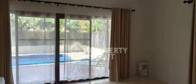 Spacious living room with pool view through large glass doors, perfect for relaxation and entertainment.