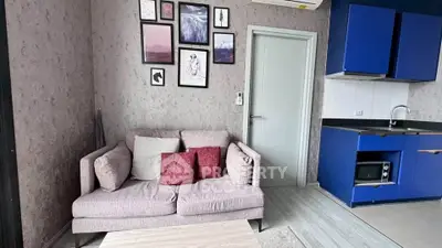 Modern living room with stylish decor and compact kitchen in a cozy apartment.