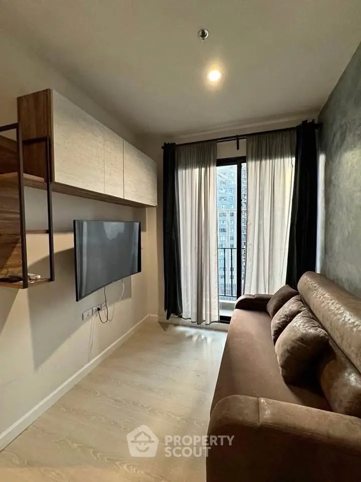 Modern living room with sleek design, featuring a wall-mounted TV and access to a small balcony.