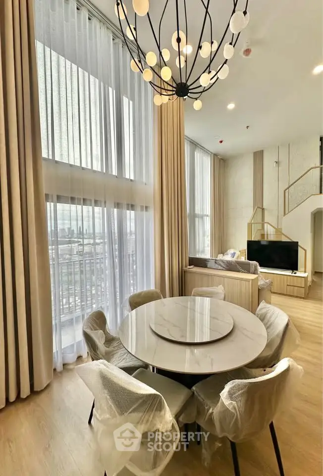 Luxurious modern living room with high ceilings and elegant chandelier in a stylish apartment.