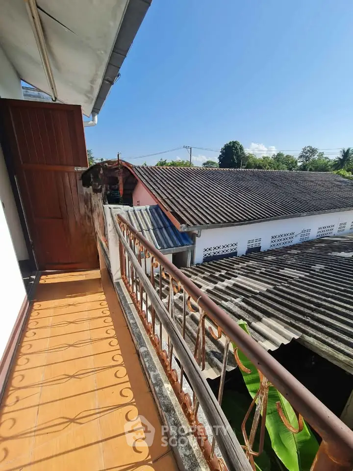 Charming balcony with rustic railing and scenic rooftop views under a clear blue sky.