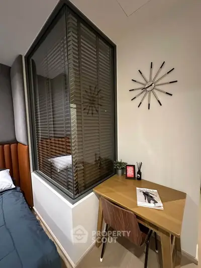Modern bedroom with stylish desk and unique wall clock, featuring a cozy bed and elegant decor.