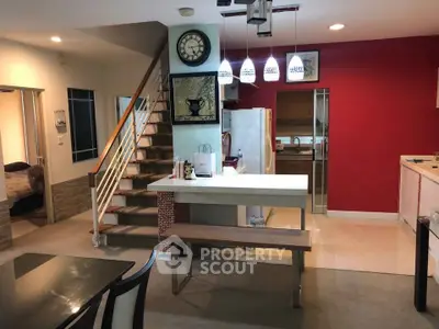 Modern open-plan kitchen and dining area with stylish lighting and staircase
