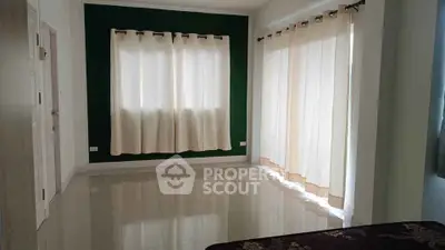 Spacious bedroom with large windows and elegant curtains in modern home.