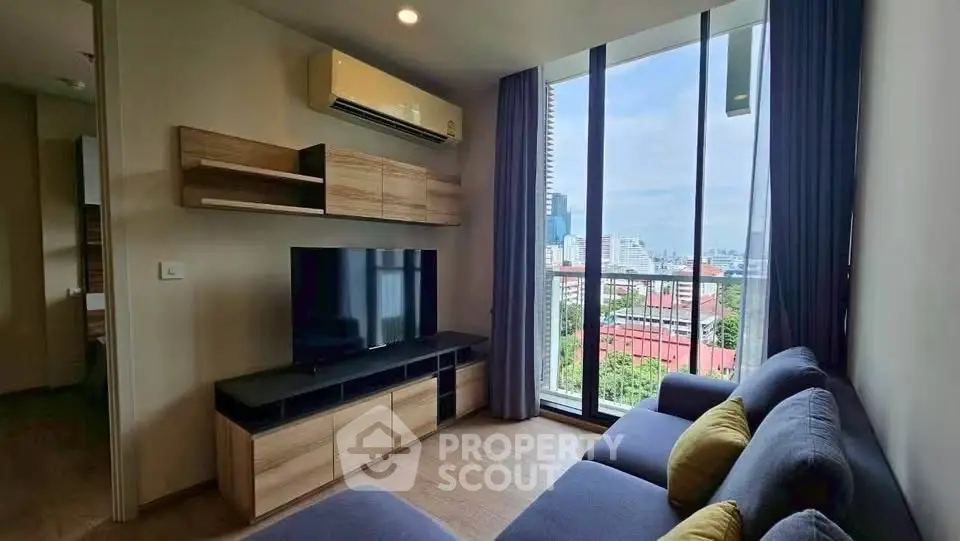 Modern living room with large windows and city view, featuring stylish furniture and air conditioning.