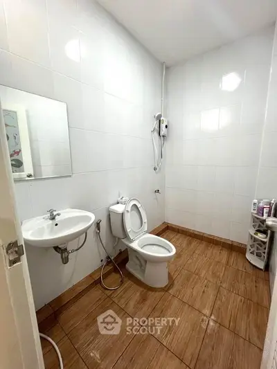 Spacious bathroom with modern fixtures and tiled flooring, featuring a wall-mounted sink and toilet.