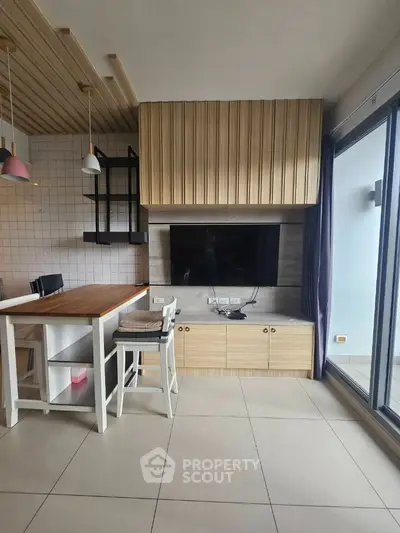 Modern living room with stylish wooden accents and large TV, featuring open layout and balcony access.
