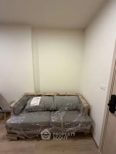 Cozy corner with a new sofa wrapped in plastic, perfect for a modern living room setup.