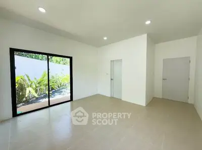 Spacious unfurnished room with large window and garden view, perfect for customization.