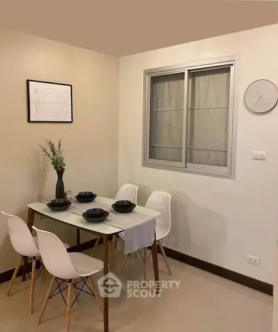 Modern dining area with sleek table and chairs, minimalist decor, and wall art.